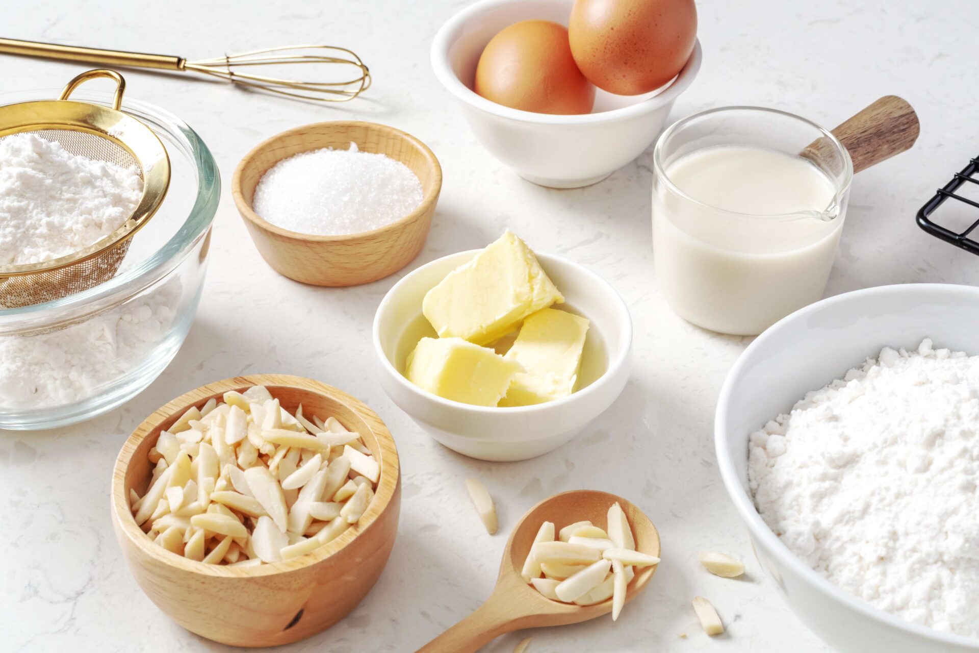 Slivered almonds in bowl next to baking ingredients