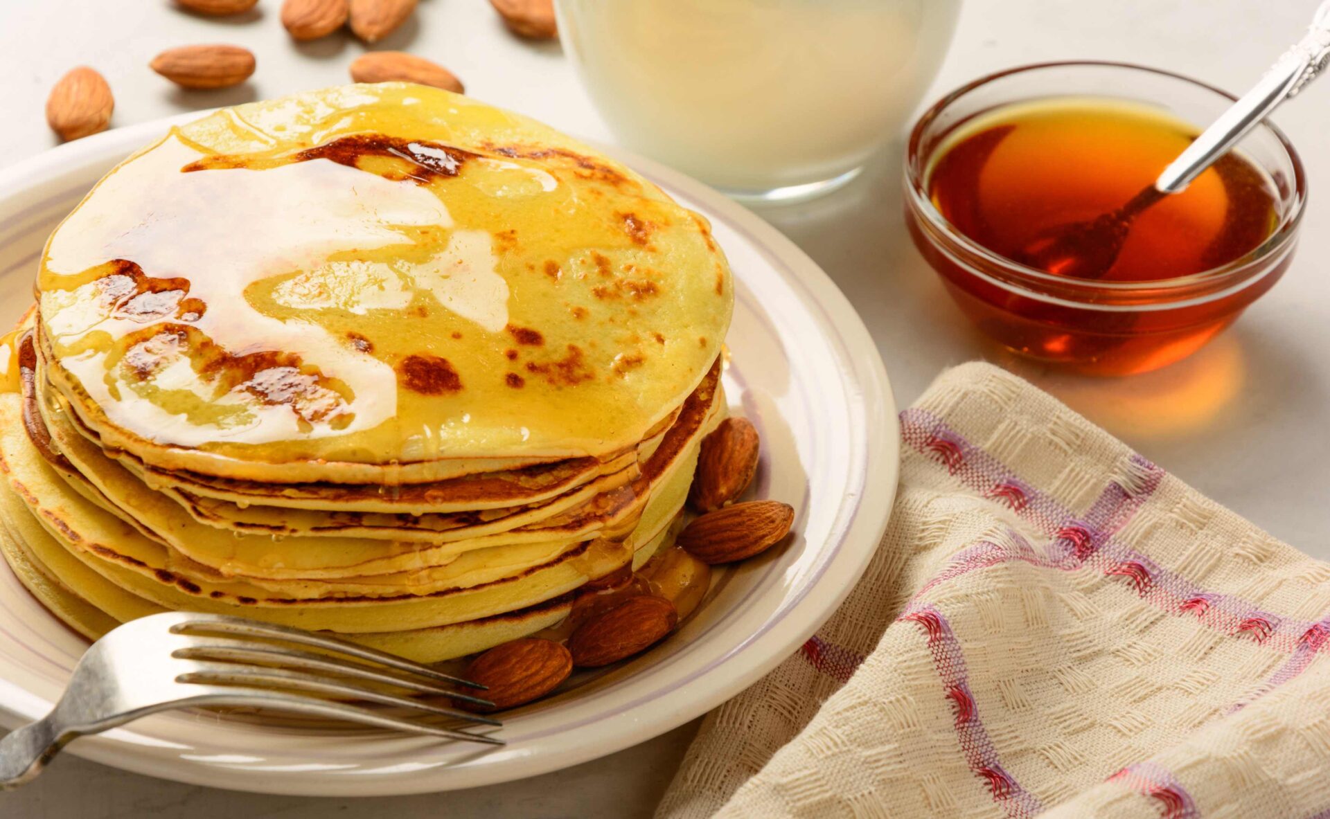 Plate of pancakes with almonds and a bowl of syrup - Organic Almond Flour Baking Mixes