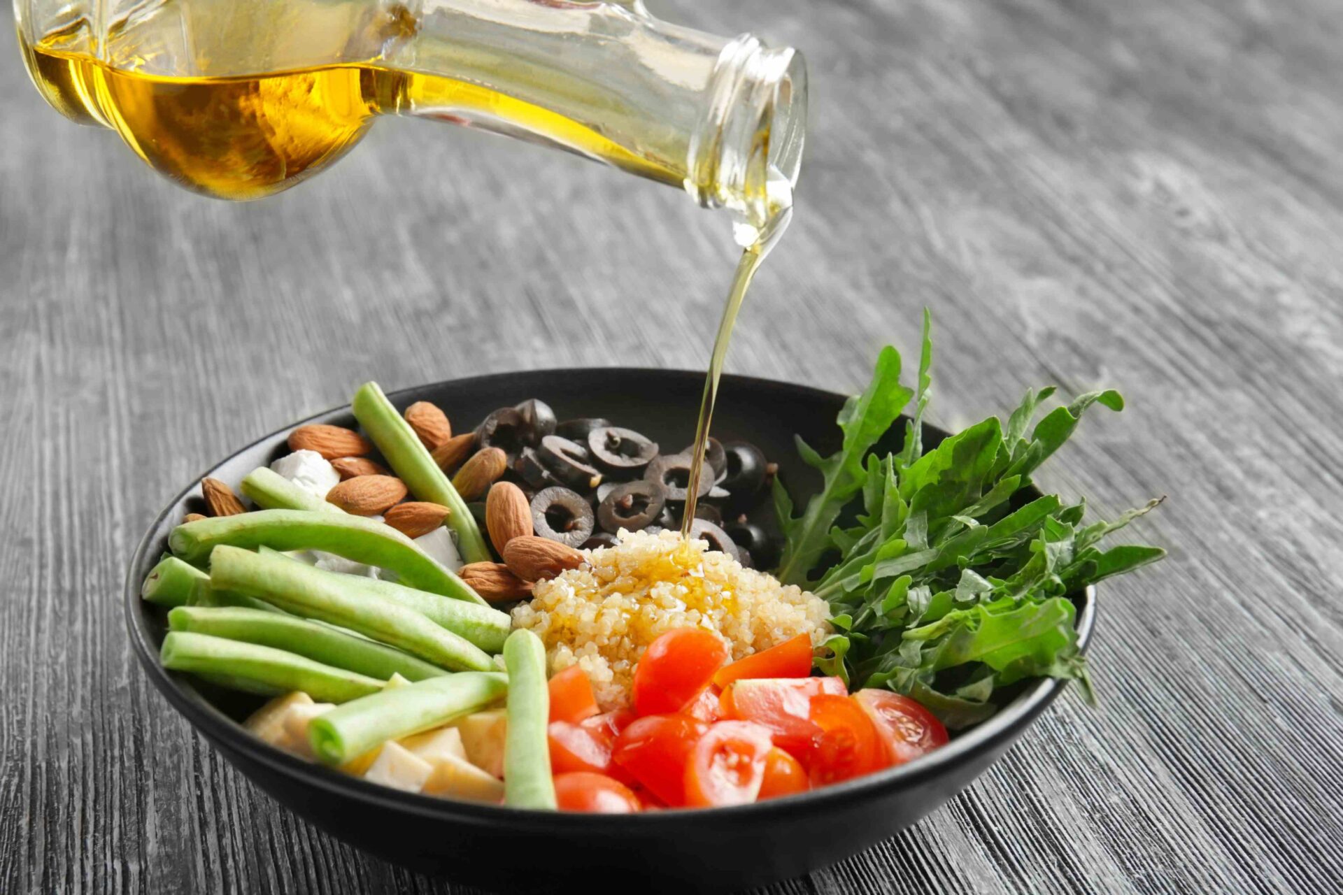 A bowl of Salad with Almond Oil Dressing Being Poured On Top - Treehouse Almond Oil
