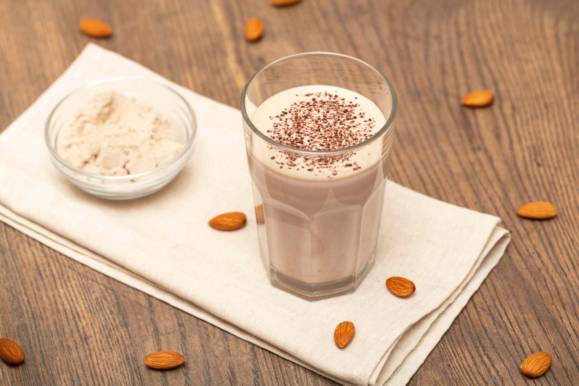 A Bowl of Almond Protein Powder next to a Glass of a Protein Shake - Protein Shakes and Smoothies