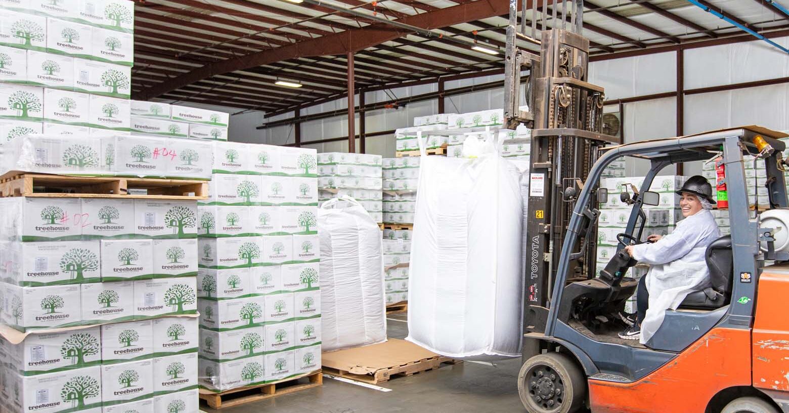 Forklift lifting a Super Sack of almond products in front of almond boxes in storage