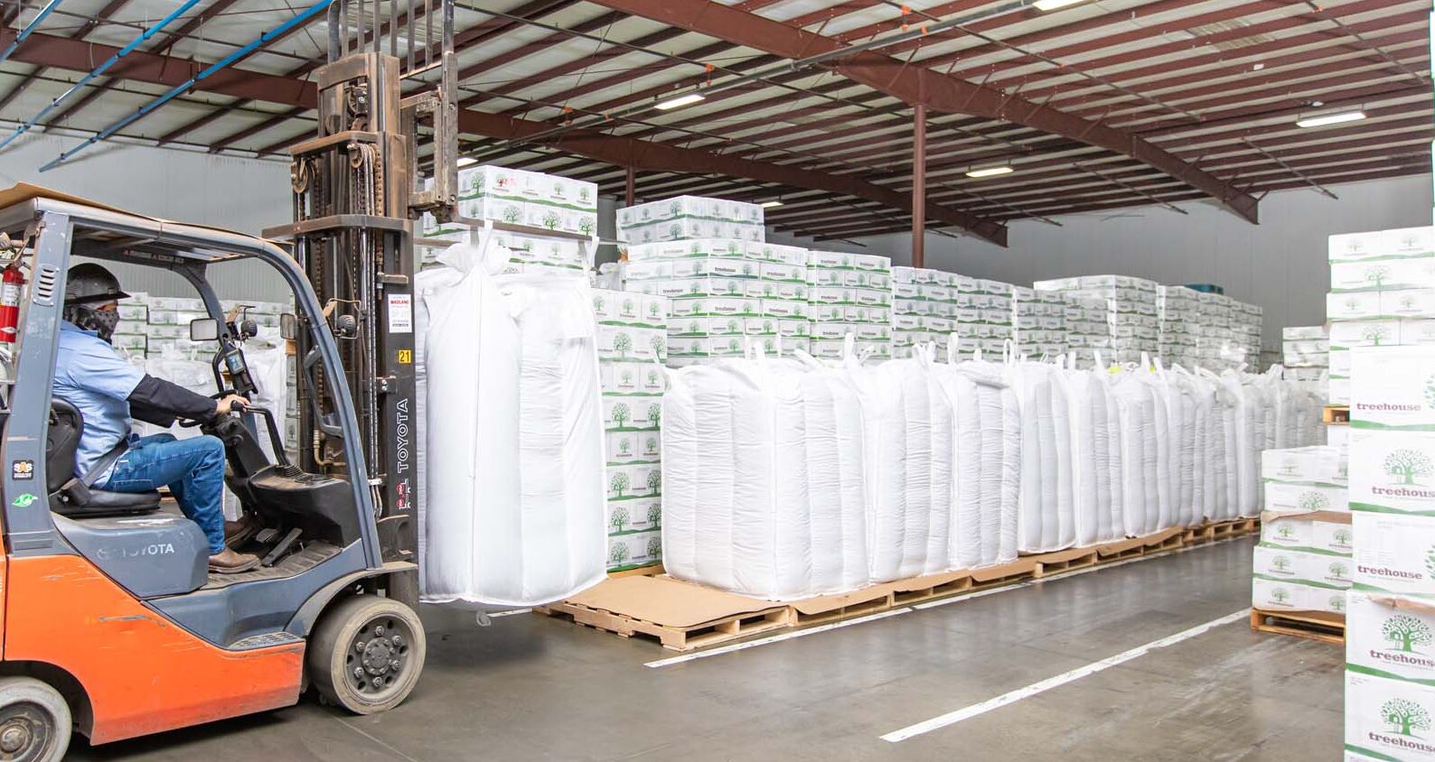 Man lifting a Super Sack of almonds with forklift in warehouse storage facility