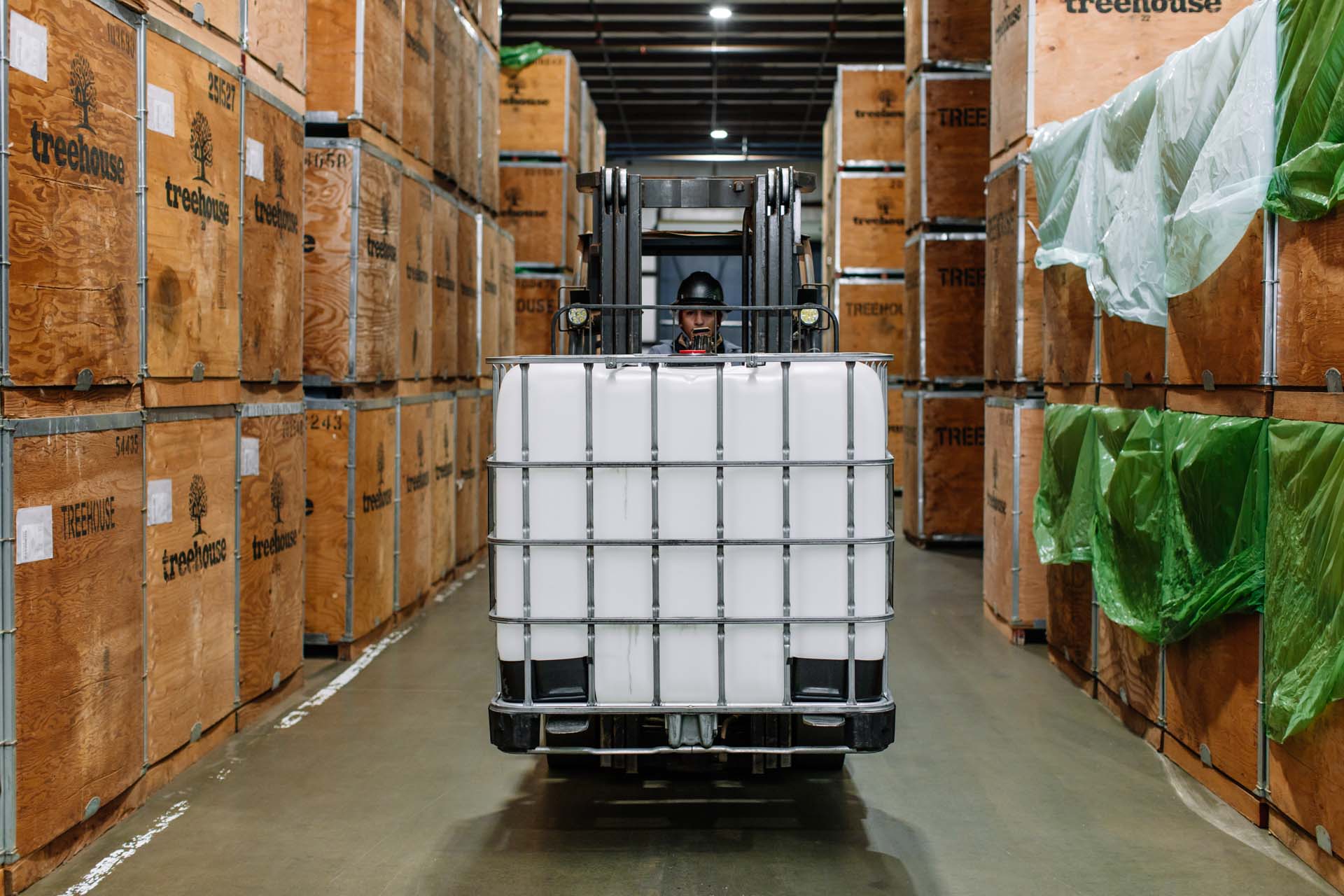 Treehouse employee carrying IBC tote on forklift