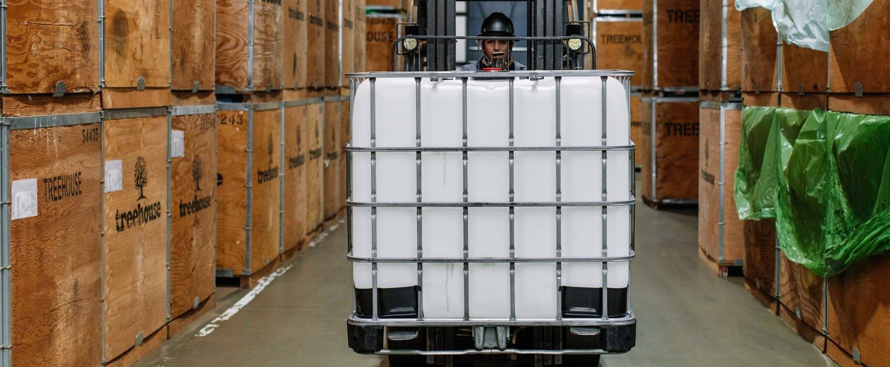 Treehouse employee with IBC Tote on forklift