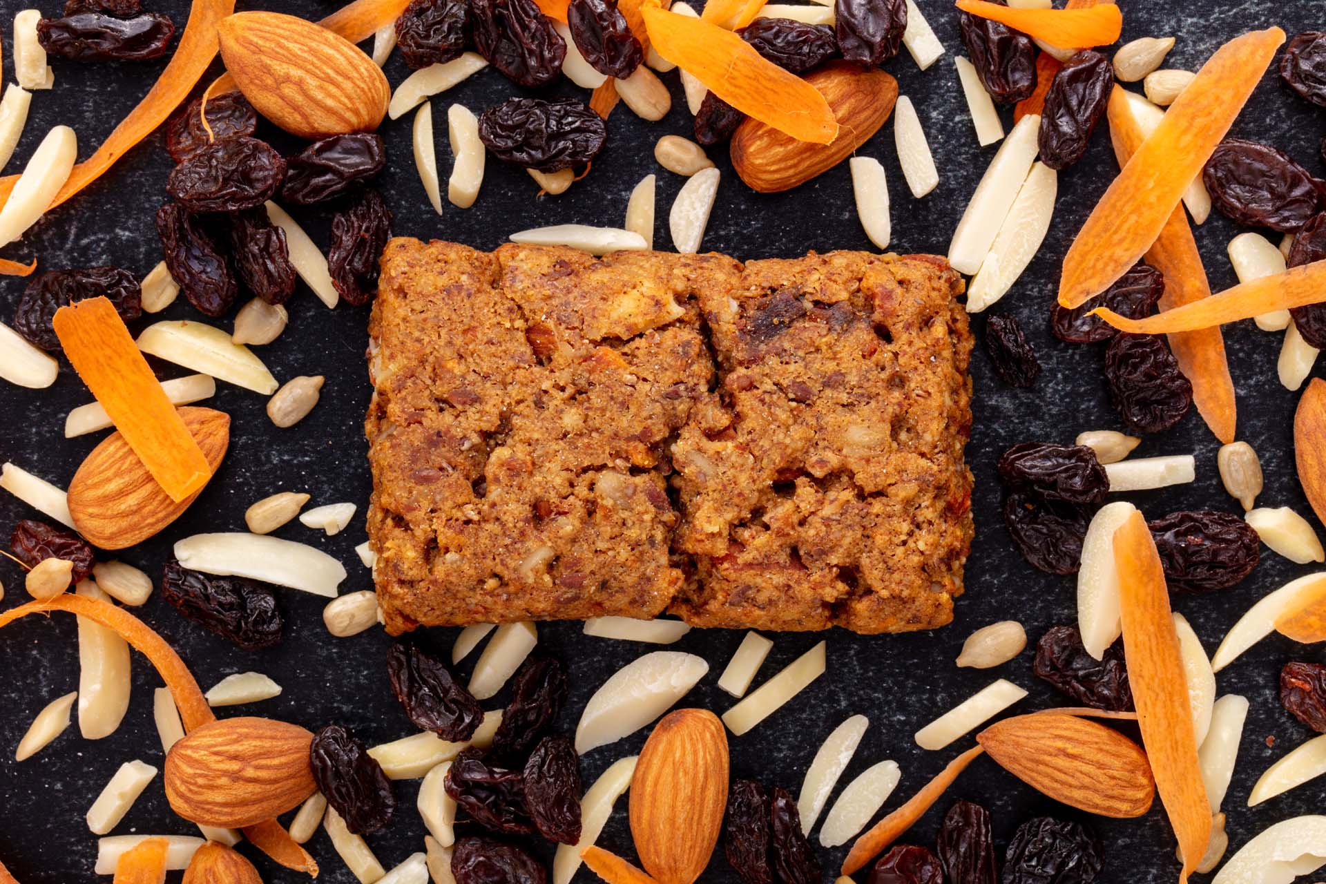 Soft Nutrition Bar Surrounded by an Assortment of Whole, Halved, Slivered, and Diced Almonds