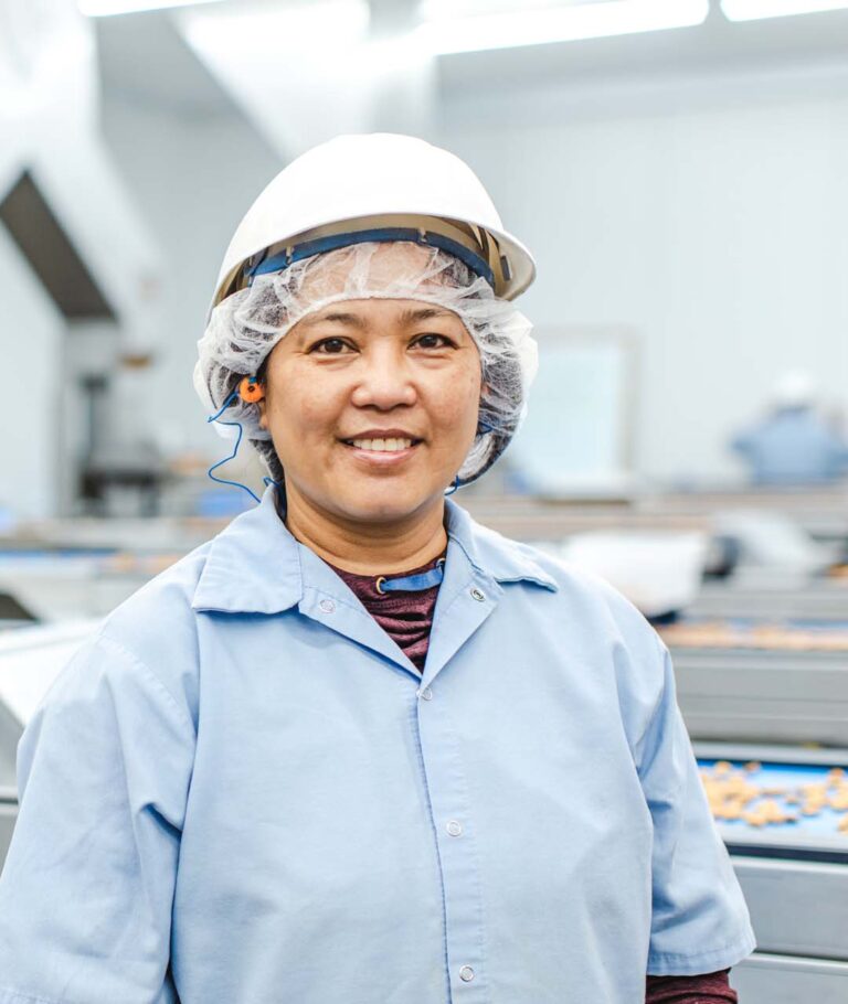 Treehouse employee wearing a hard hat smiling in front of a sorting line