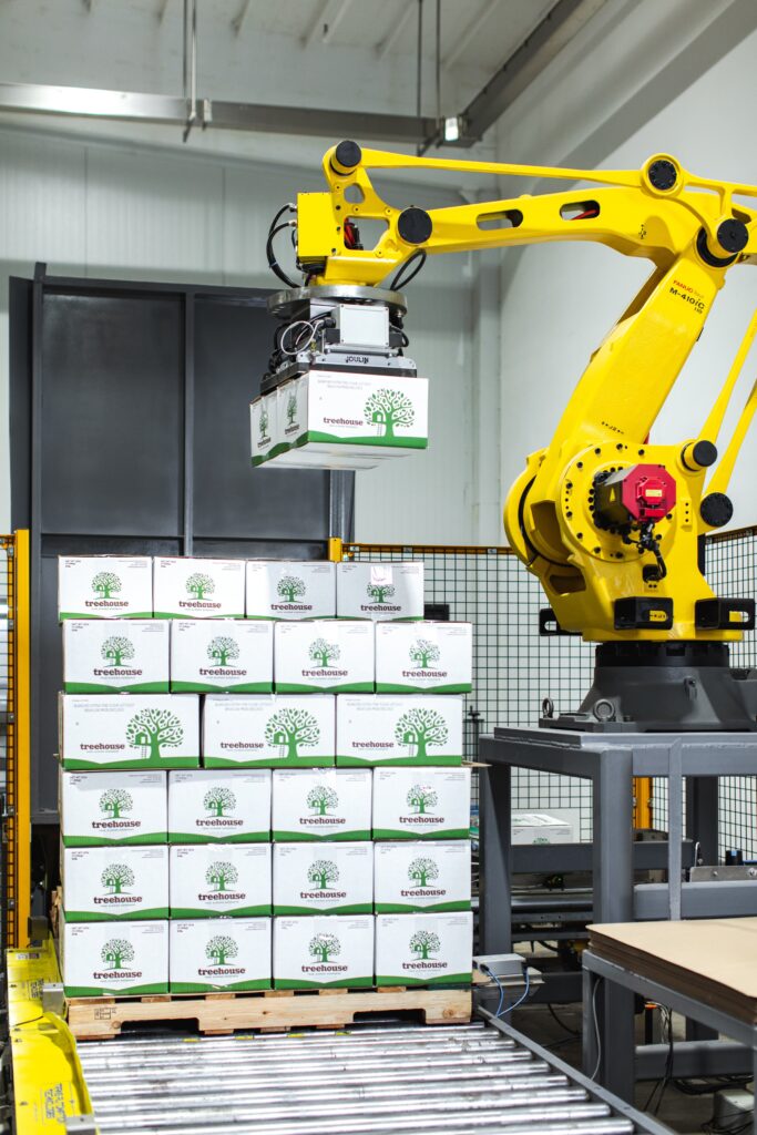 machine lifting boxes of Treehouse Almonds and stacking them