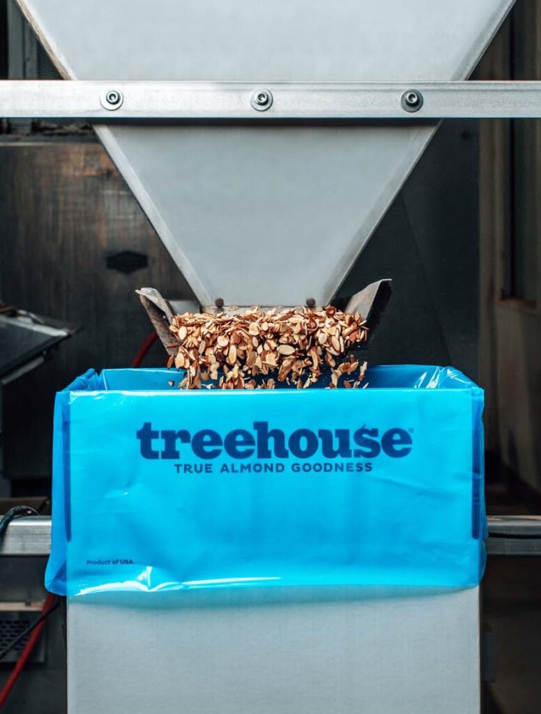 Almonds being poured into a Treehouse Almonds box for shipping