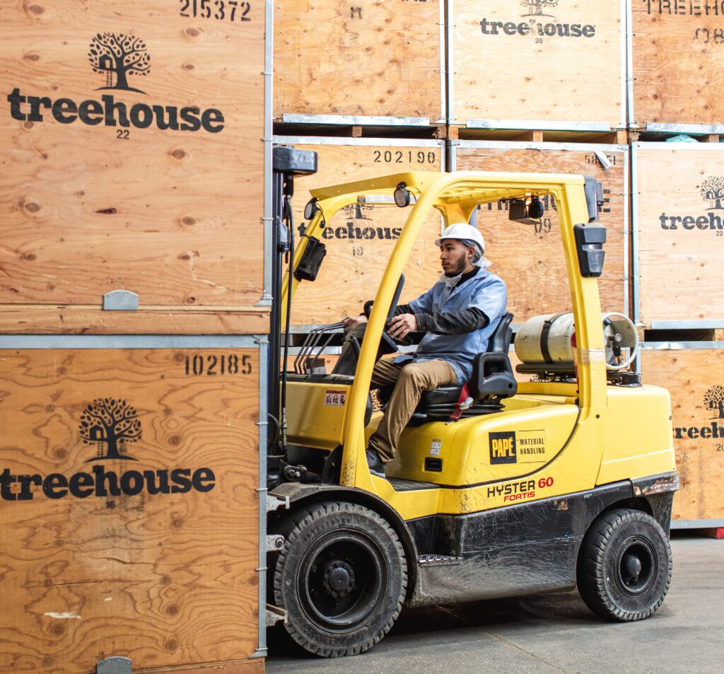 Treehouse employee driving a yellow forklift picking up a box of almonds