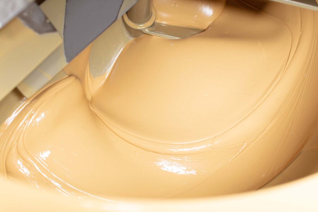 Light roasted blanched almond butter swirling in production equipment