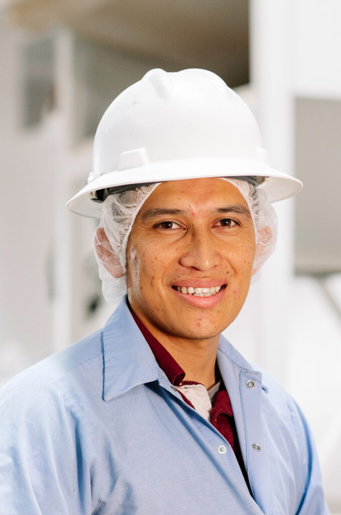 Treehouse employee man wearing a hard hat & smiling at the camera